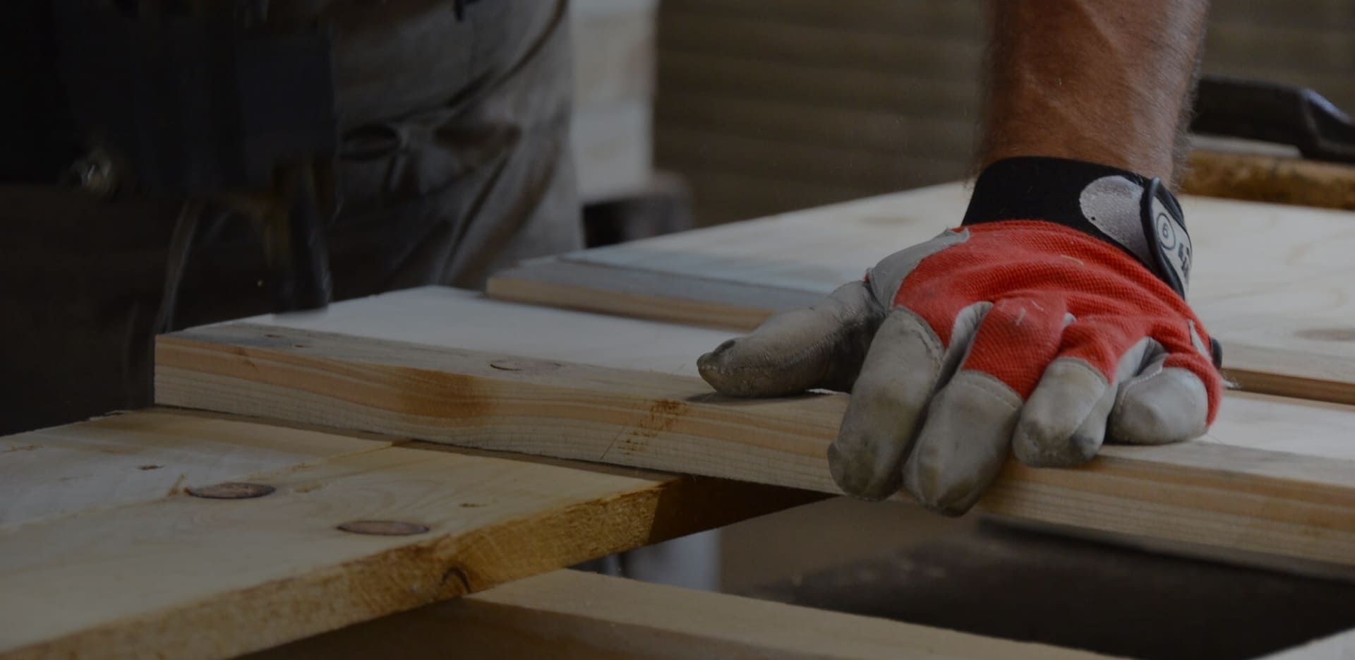 Ein Mann mit Handschuhen hält ein Holzbrett zum Schneiden bereit
