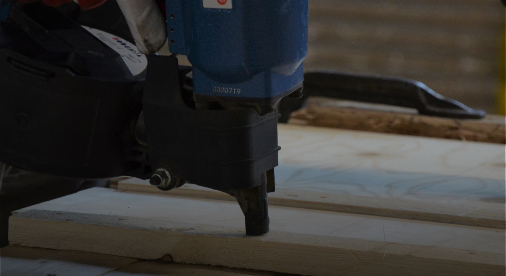 Maschine hämmert Nägel in eine Holzplatte